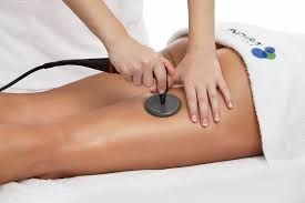 Close-up of a person receiving a leg massage with a circular device in a spa setting.