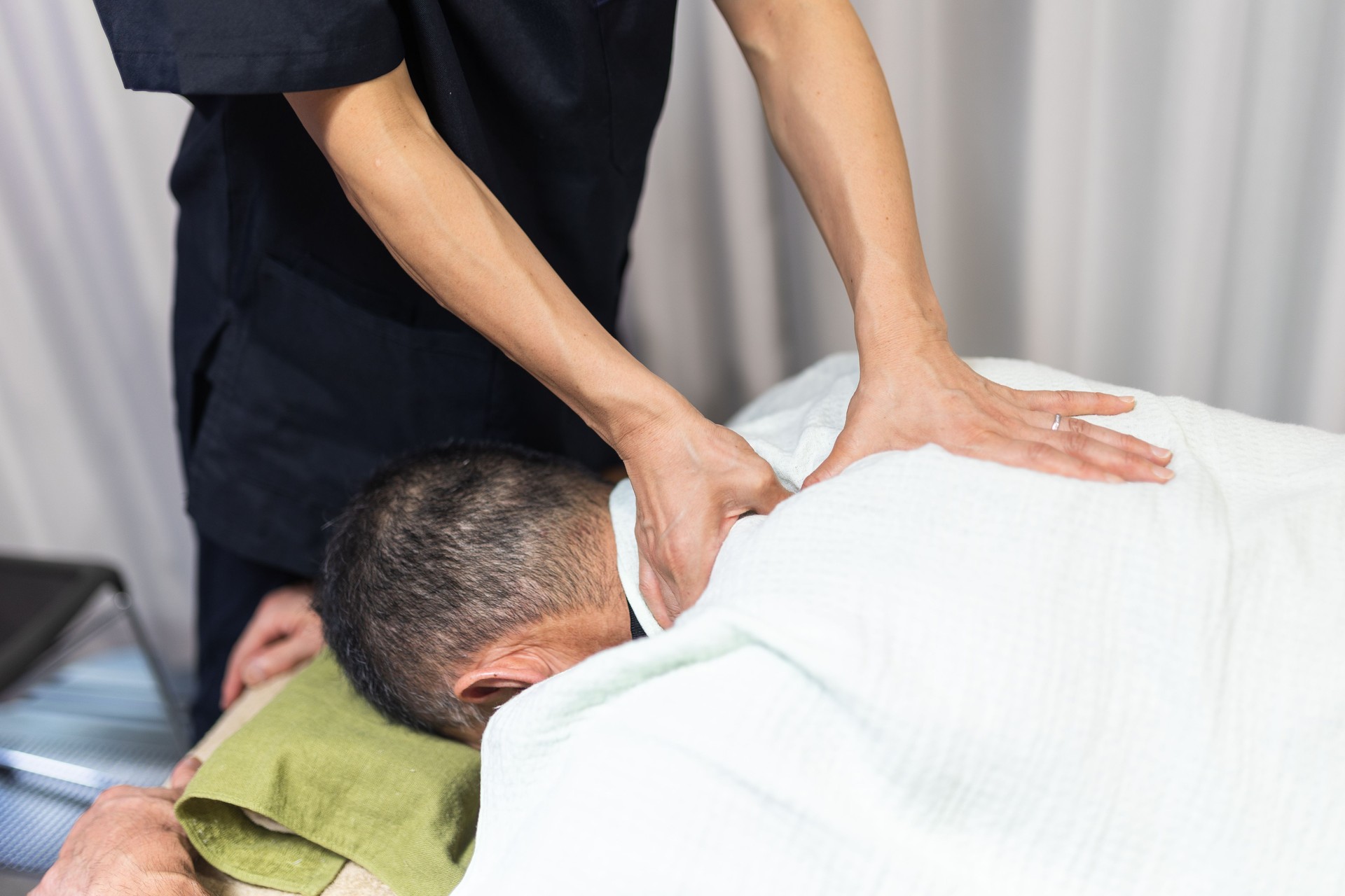 A massage therapist massaging a patients neck and shoulders