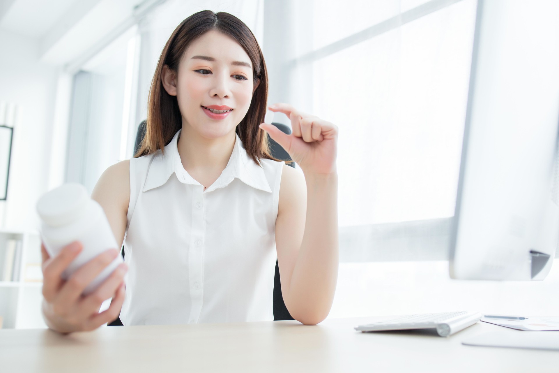 Asian woman holding pills in her hand