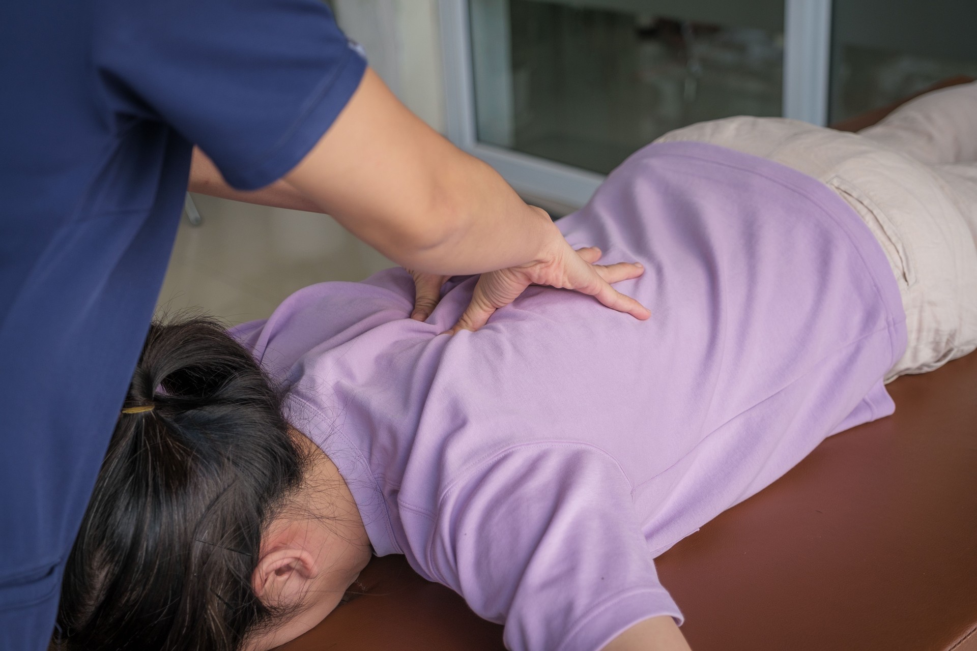 Female doctor or physiotherapist giving a treatment chiropractic back and shoulder adjustment to woman patients on medical visit